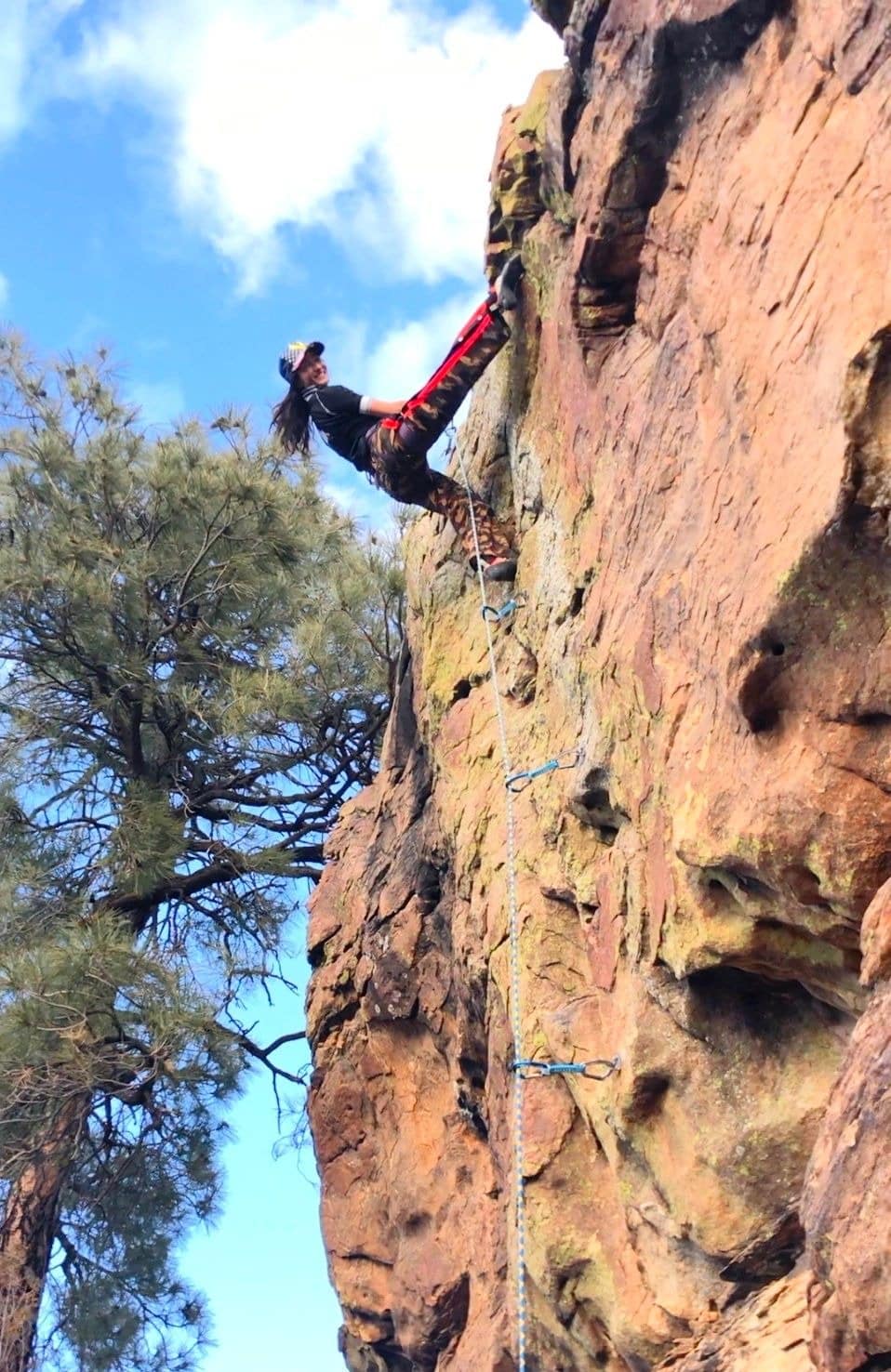 Person rock climbing on steep cliff outdoors.