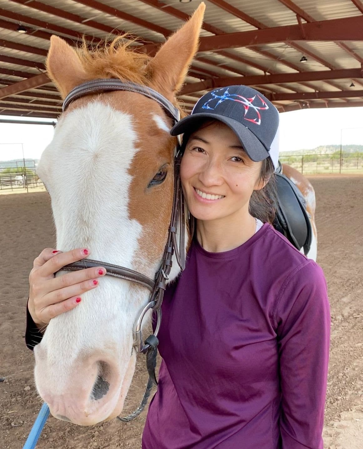 Woman smiling with horse at equestrian center.