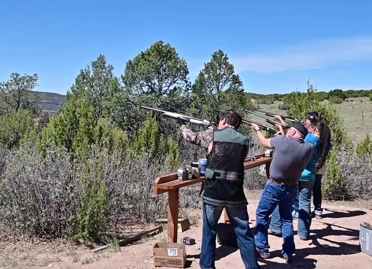 People practicing clay pigeon shooting outdoors.