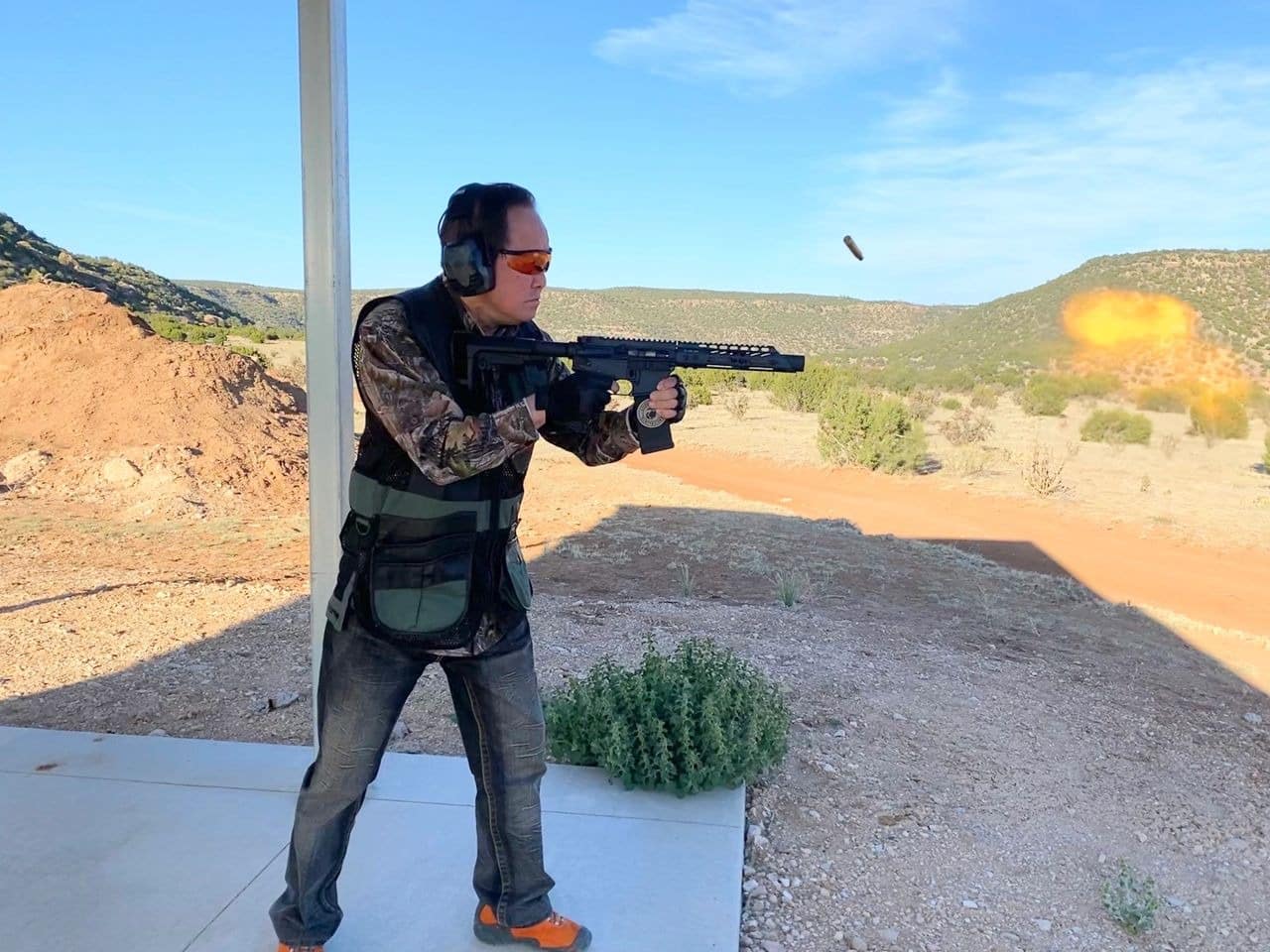 Man firing rifle outdoors with muzzle flash