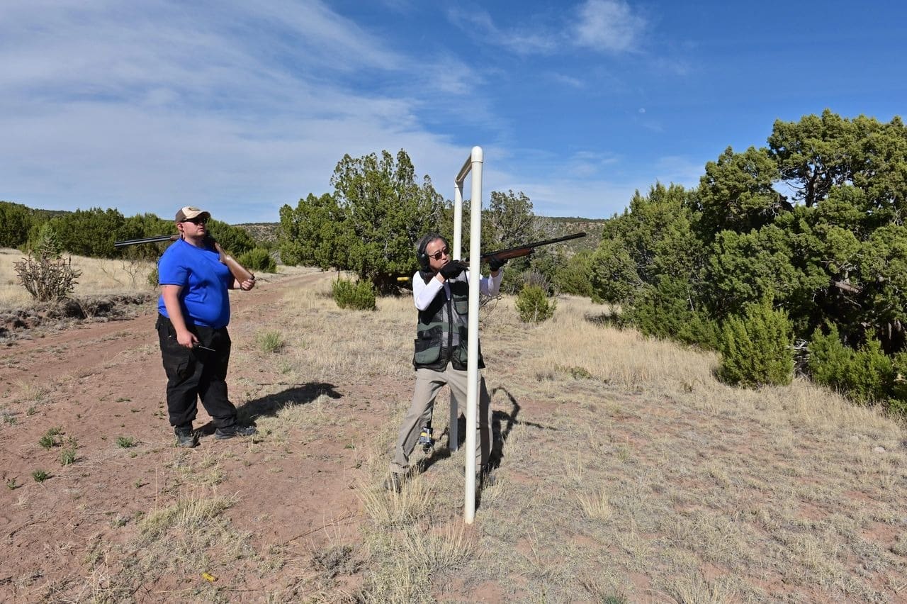 Men practicing clay pigeon shooting outdoors.