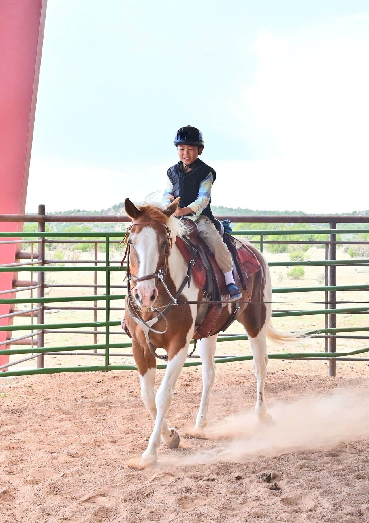 Child riding horse in equestrian arena.