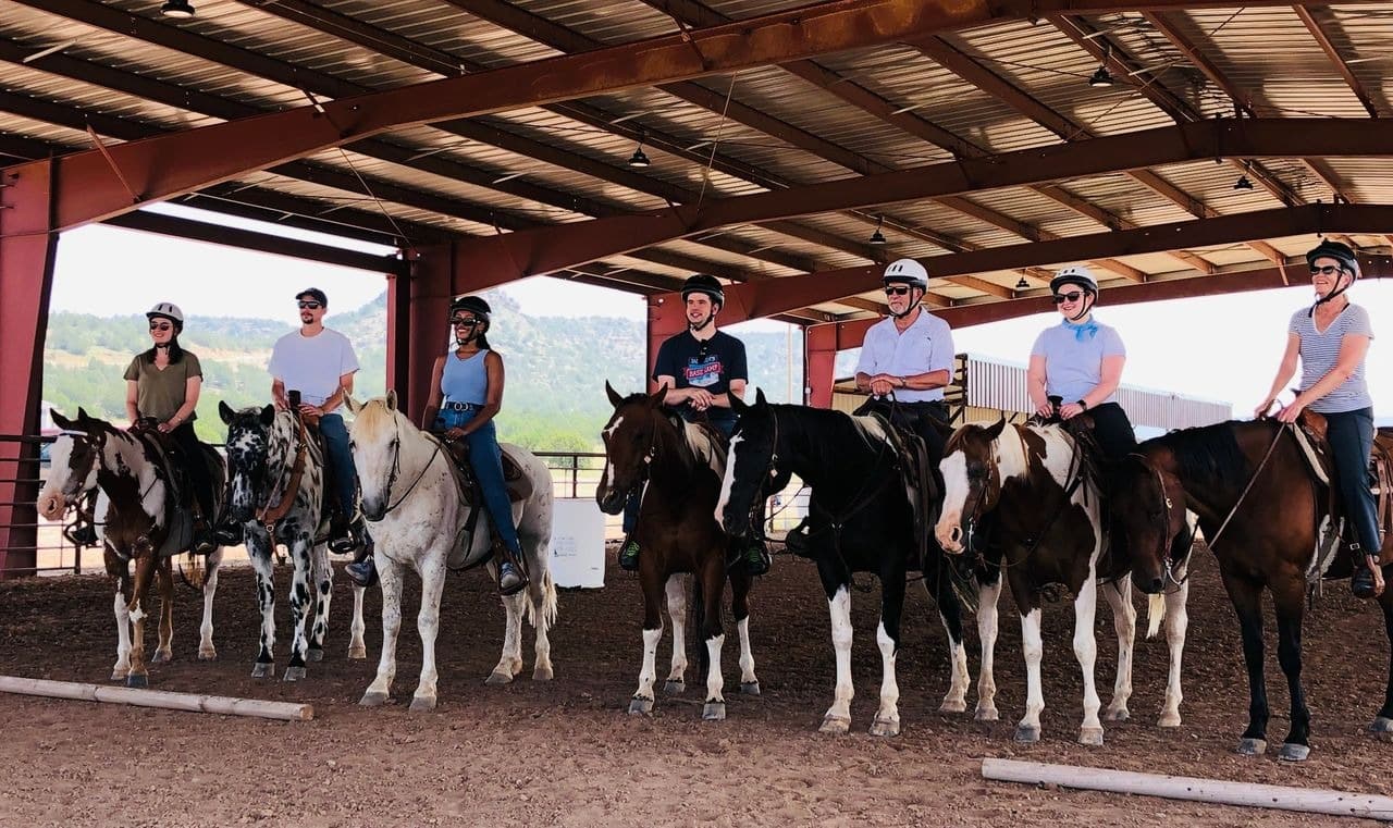 Group horseback riding lesson in covered arena.