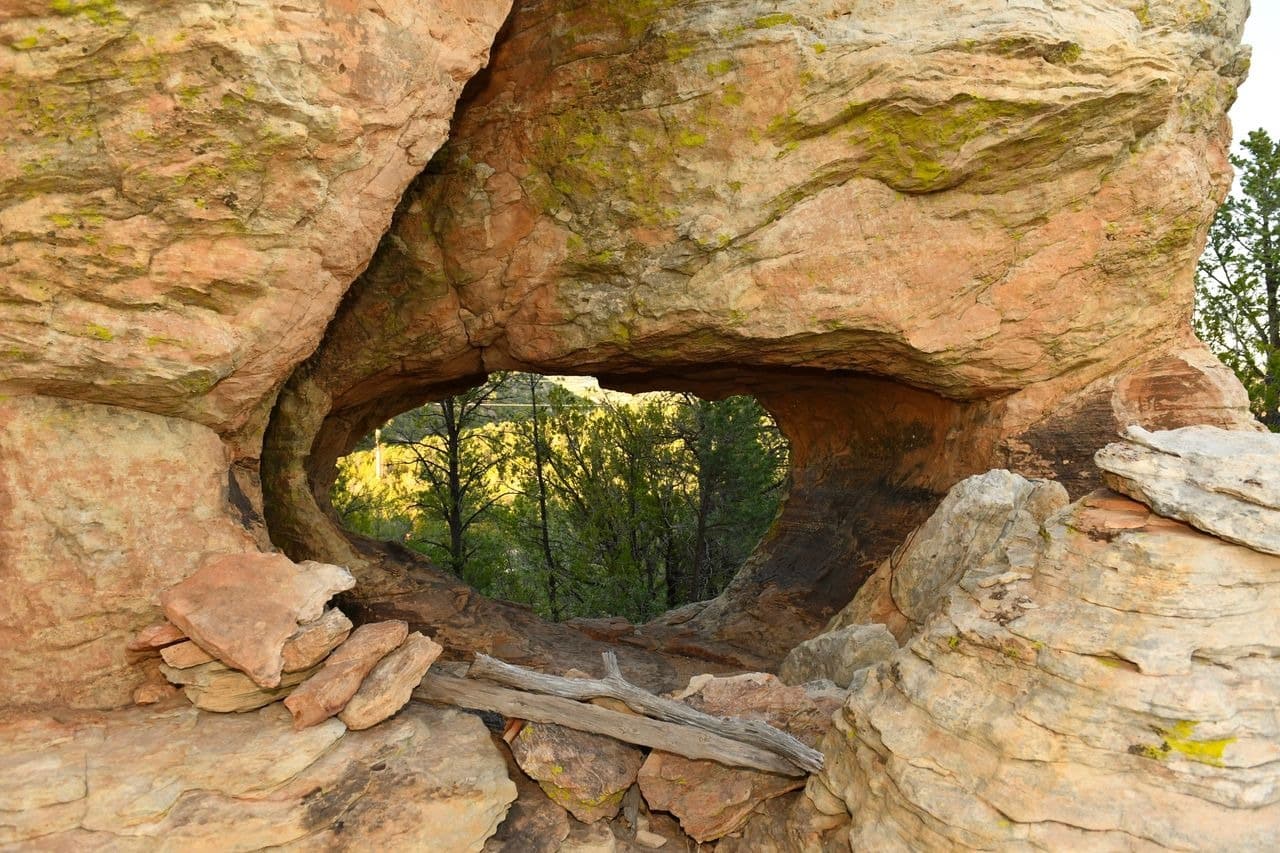 Natural stone arch in forested landscape.