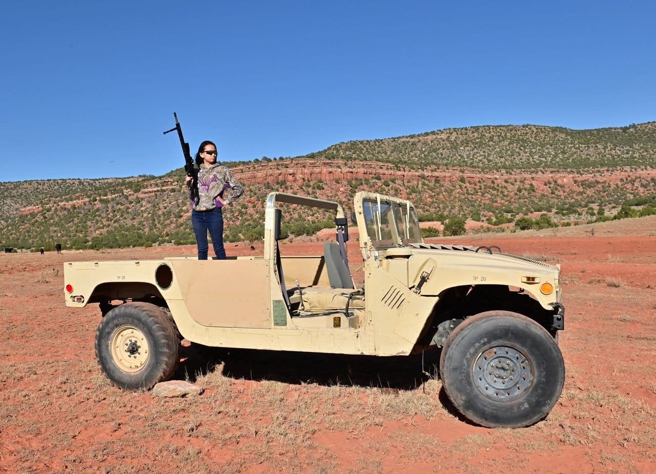 Person standing on vintage military jeep in desert.