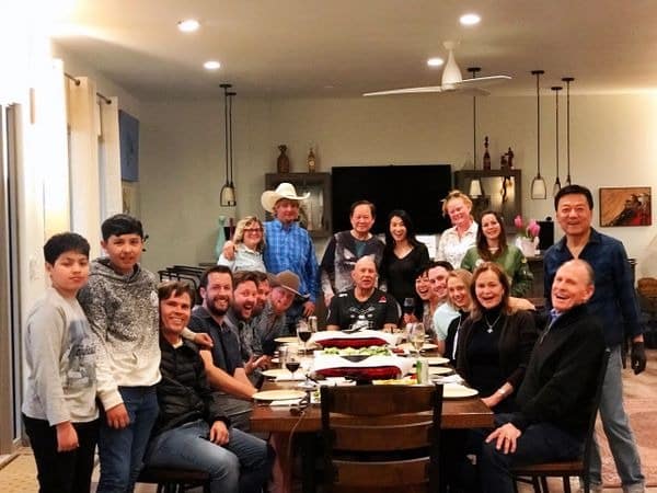 Family and friends gathering around dinner table indoors.